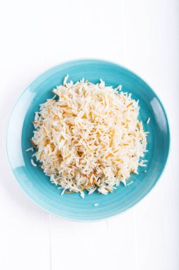 Beyaz arka planda seramik bir kase veya tabakta servis edilen pişmiş basmati pilavının üst görüntüsü.