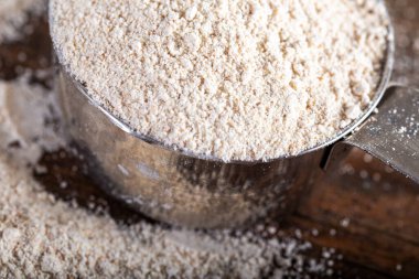 Einkorn Siyez doğal arka planda metal ölçü kabında tam buğday unu.