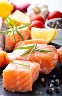 Siyah kesme tahtasında taze çiğ somon filetosu, limon ve baharatla. Sağlıklı gıda konsepti. Görüntüyü kapat