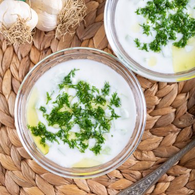 Tzatziki sosu, salatalık dilimleri ve cam kasede zeytinyağlı Türk Kakik yoğurdu. Üst görünüm.