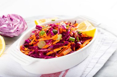 Kırmızı lahana ve yeşil soğanlı havuç salatası ve masada limonlu domates..