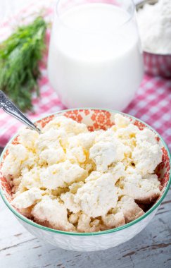 Peynir ya da süzme peynir beyaz kâse içinde, tahta masada bir bardak süt, yakın çekim manzaralı..