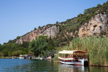 Dalyan, Mugla / Türkiye - 09 / 26 / 2020: Lycian kaya mezarlarının manzarası ve Türkiye 'deki Dalyan Nehri üzerinde turistlerle tekne gezileri.