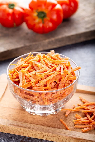 Vegetable noodles with tomato. Uncooked vegetable noodles in glass bowl on wooden board.