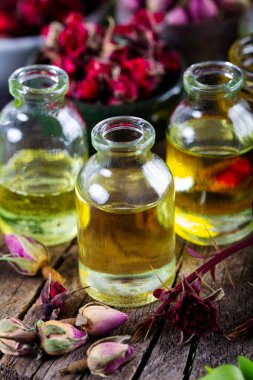 Aromaterapi tedavisi için gerekli yağlı kurumuş bitkiler. Bir şişe gül yağı ve kurumuş gül yaprakları.. 