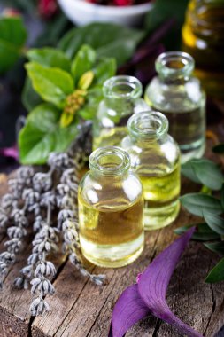 Ahşap arka planda küçük şişelerde lavanta yağı. Aromaterapi aletleri, yağlı şişeler ve lavanta çiçekleri..
