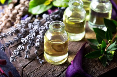 Ahşap arka planda küçük şişelerde lavanta yağı. Aromaterapi aletleri, yağlı şişeler ve lavanta çiçekleri..