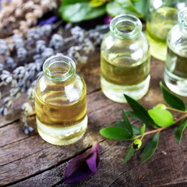 Ahşap arka planda küçük şişelerde lavanta yağı. Aromaterapi aletleri, yağlı şişeler ve lavanta çiçekleri..