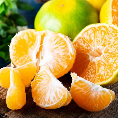 Olgun Mandarin meyveleri soyuldu ve mandalina meyveleri ve yaprakları ile eski kırsal görünümlü kerestelerin üzerine yerleştirildi. Kış meyveleri.