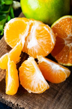 Olgun Mandarin meyveleri soyuldu ve mandalina meyveleri ve yaprakları ile eski kırsal görünümlü kerestelerin üzerine yerleştirildi. Kış meyveleri.