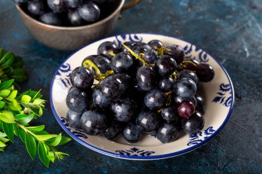 Taze siyah üzüm ve yapraklar koyu arkaplanda..