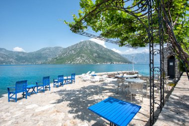 Deniz kenarında dağ manzaralı boş bir kafe. Karadağ, Kotor Körfezi