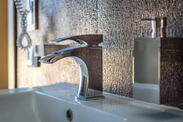 Grifo de agua junto a un vaso para dispensador de jabón líquido — Foto de Stock