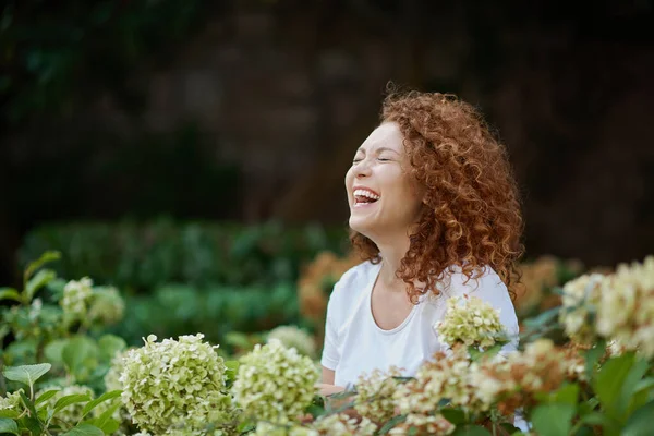 Portrait of a laughing young woman outside in a garden — Stock Photo, Image