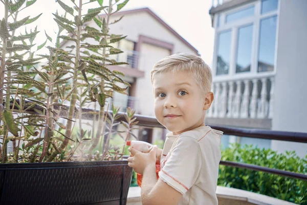 Sorrindo jovem criança regando ervas na varanda — Fotografia de Stock
