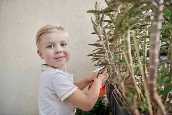 Sorrindo jovem criança regando ervas na varanda — Fotografia de Stock