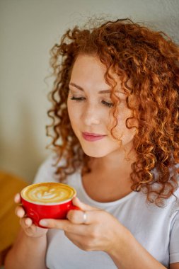 Genç bir kadın kahve içiyor.