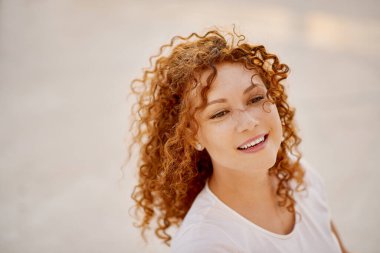 Kızıl saçlı kadın önüne bakıyor.