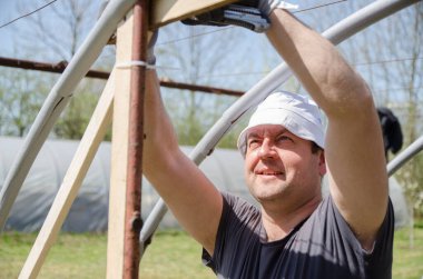 Erkekler baharda bahçede yaprak yapmak için bir yapı inşa ederler.