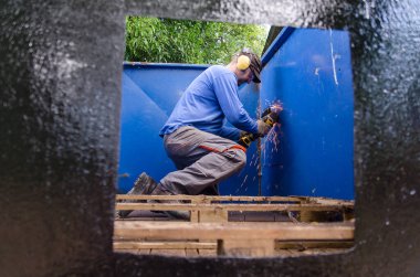 Açı öğütücü kullanan adam, işçi koruyucu ekipman kullanır. Dışarıda..