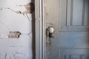 Evin eski duvarı alçının hangi kısmının düştüğü ve yıkıldığı, yakın plan eski bir bina, kapalı beyaz ahşap kapı