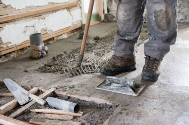 Kirli iş, beton döşeme üretimi, bir işçinin alet ve bacaklarına bakış açısı, kapat