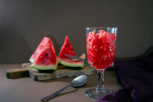 Karpuz suyu, yemek kaşığı, ahşap kesim tahtası, kumaş.