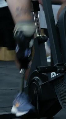 Kharkiv, Ukrayna - 12 Eylül 2025: Spor salonunda bacak ampütasyon trenleri olan bir adam, bacak yerine bisiklet tekerleği protezi çeviriyor. Rehabilitasyon, protez, eğitim, aktif yaşam tarzı