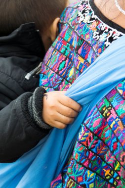 Guatemala, Şehir - Aralık 06, 2017. Sırtında çocuğu olan genç bir Maya kadını tipik bir Guatemala elbisesi giyiyor, Orta Amerika 'da, Latin bir kadın, anne. BÖLÜM