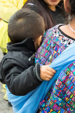 Guatemala, Şehir - Aralık 06, 2017. Sırtında çocuğu olan genç bir Maya kadını tipik bir Guatemala elbisesi giyiyor, Orta Amerika 'da, Latin bir kadın, anne. BÖLÜM