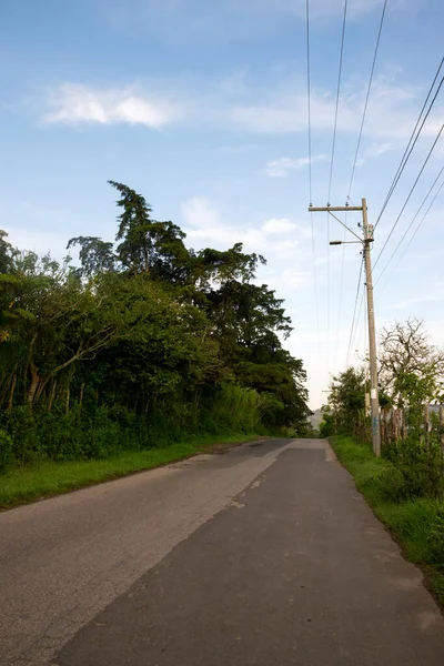Rural road in Central America, electric light poles, high voltage cables, deteriorated asphalt