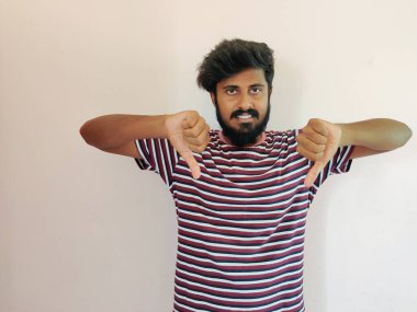 Soyunmuş tişörtlü başarılı bir Hintli sakallı adamın portresi, beyaz bir arka planda izole edilmiş, sevmeme belirtileri gösteriyor.