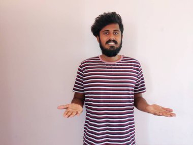 Hintli gülen sakallı adam elinde ürünler gösteriyor. Adam soyulmuş tişört giymiş. Beyaz arkaplanda izole.