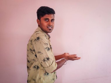 Resmi olarak giyinmiş gülümseyen adam pembe arka planda ürünler gösteriyor. Boşluğu kopyala