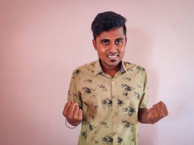 Pembe arka planda tek başına duran heyecanlı Hintli genç adam, kazanan hareketi yapıyor. Gün ışığı