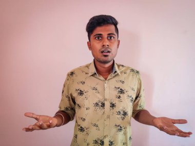 Şok edici bir yüz ifadesi olan Güney Hintli genç adamın portresi. Pembe arka planda izole edilmiş.