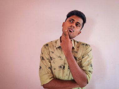 Düşünen yüz ifadesi olan temiz tıraşlı genç bir Güney Hintli adam portresi.