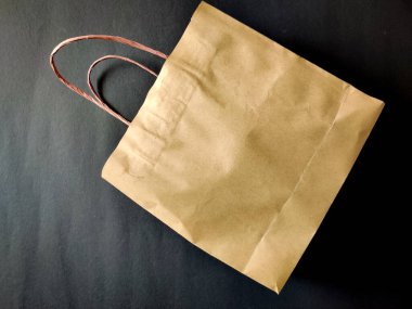 Kese kağıdı ve sapları olan kahverengi bir çanta. Siyah arkaplanda izole.