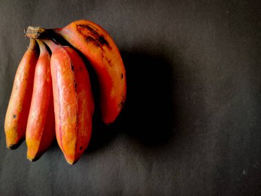 Siyah arka planda dört kırmızı muz. Boşluğu kopyala