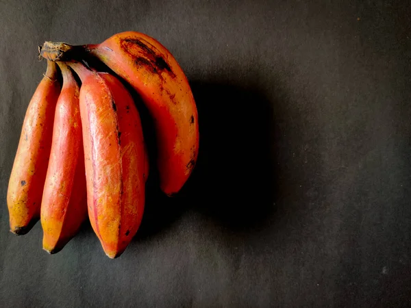 Siyah arka planda dört kırmızı muz. Boşluğu kopyala