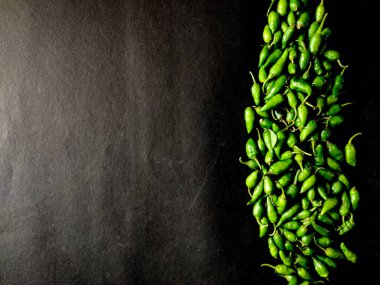 Siyah arka planda izole edilmiş bir sürü küçük yeşil biber. Boşluğu kopyala.