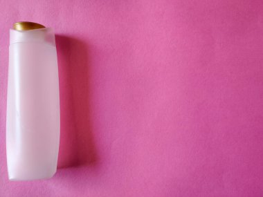 Pembe arka planda beyaz renkli şampuan şişesi. Kopyalama alanı