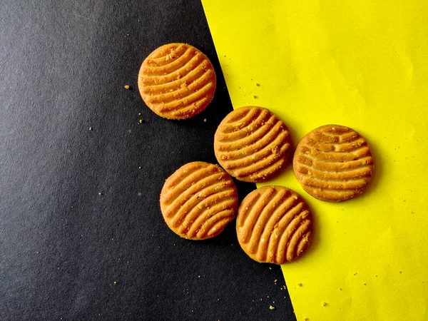 Five cashew cookies or biscuits isolated on black and yellow background