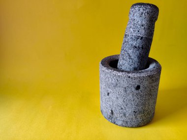 Havan ve Pestle taştan yapılmış. Sarı arka planda izole edilmiş. Boşluğu kopyala