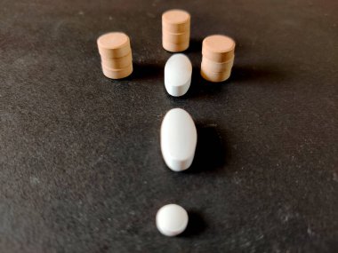 Tablet kavramı. Covid-19 Corona virüsü tedavisi. Siyah arka planda beyaz ve turuncu renkli tıbbi haplar. Seçici odak