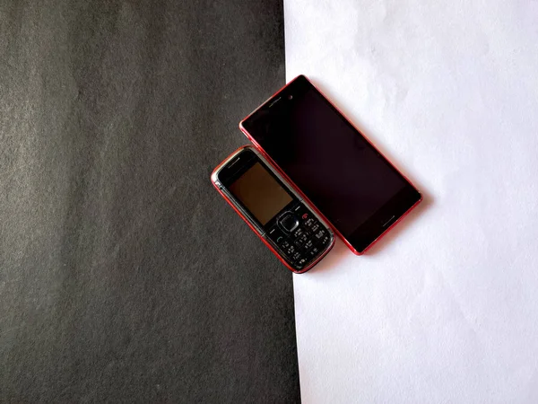 One Keypad mobile and one smart phone in different sizes isolated on white and black background. Selective focus