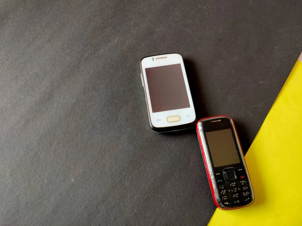 White color smart phone and red color keypad phone isolated on black background.Selective focus