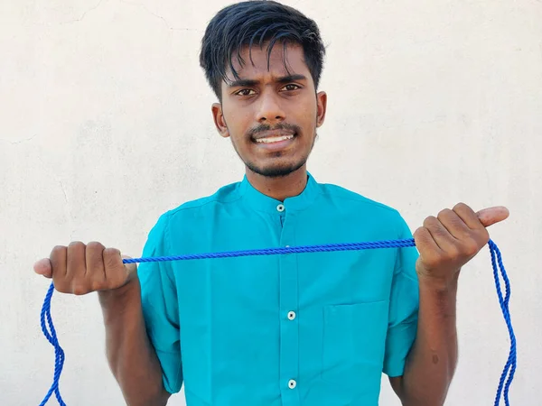 South Indian man with angry face stretching a rope with his hands.Isolated on white background.