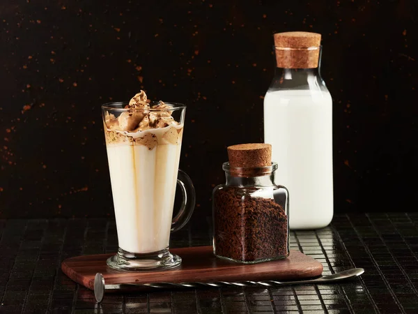 Dalgona Coffee: a layered drink made of hot milk and whipped instant coffee, on dark brown background
