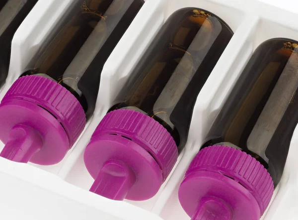 Brown vials with violet lid filled with brown liquid. Dietary supplement.